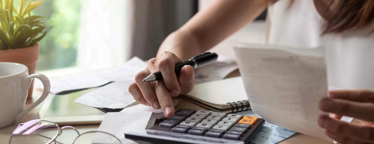 Une femme tape des montants de dépenses sur sa calculatrice
