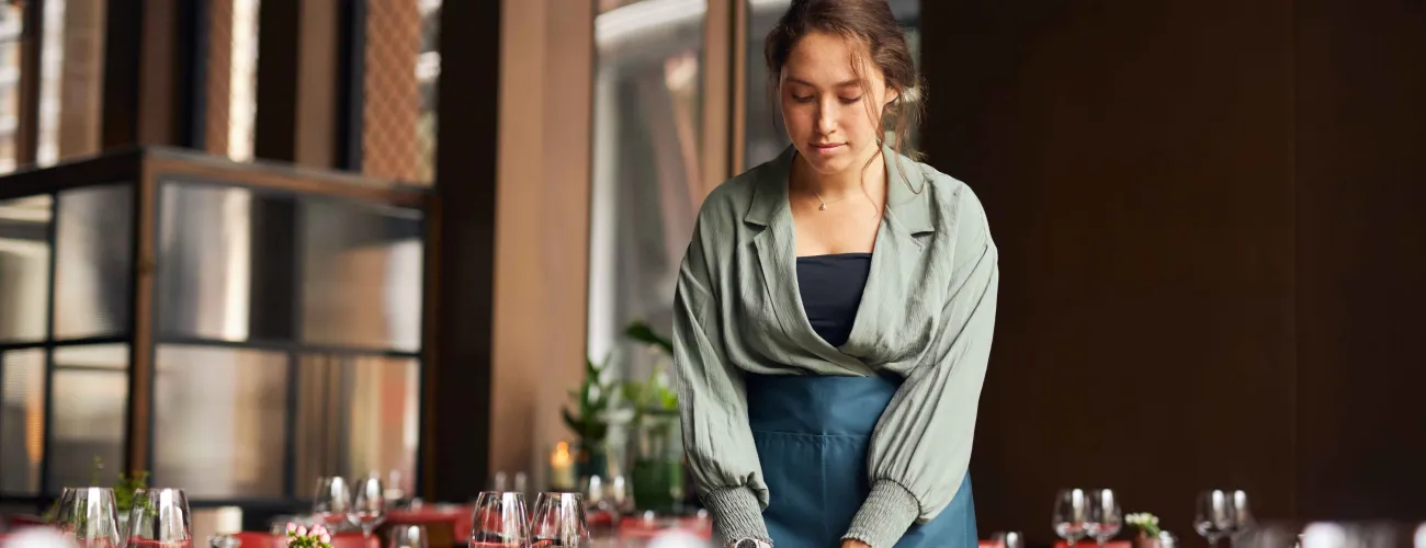 Une étudiante dresse une table de restaurant