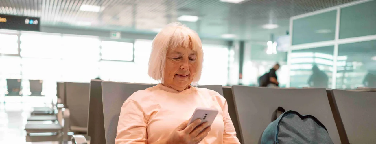Une dame assise dans un aéroport regarde son passeport