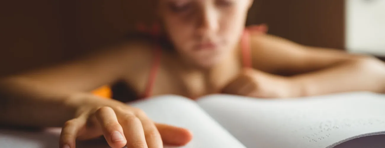 une enfant lit un livre en braille
