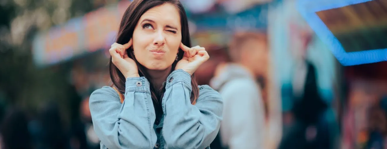 Une femme se bouche les oreilles car elle est dérangée par le bruit