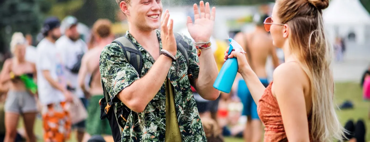 Deux personnes sont à un festival de musique et s'aspergent d'eau