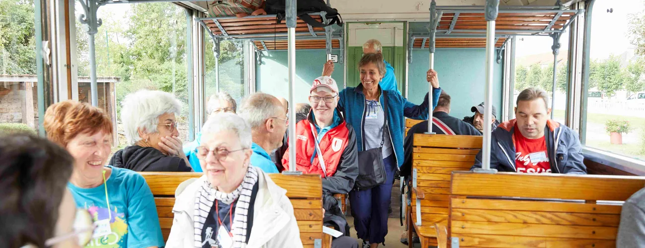 Un volontaire d'Altéo est debout dans un bus rempli de participants souriants