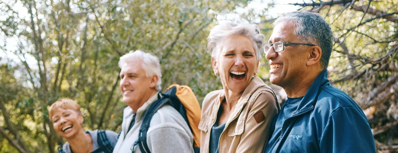 4 seniors marchent et rient en pleine nature