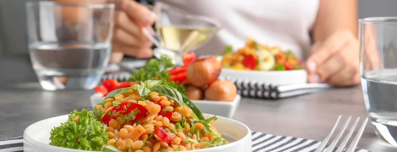 une femme verse de l'huile sur une salade avec pois chiches