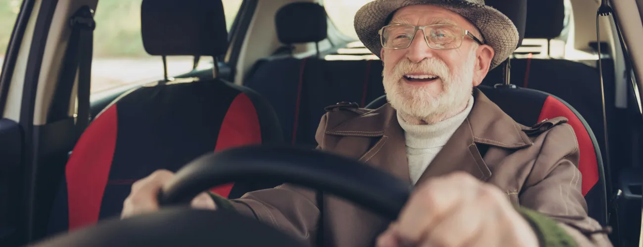 Un homme âgé tout sourire au volant de sa voiture