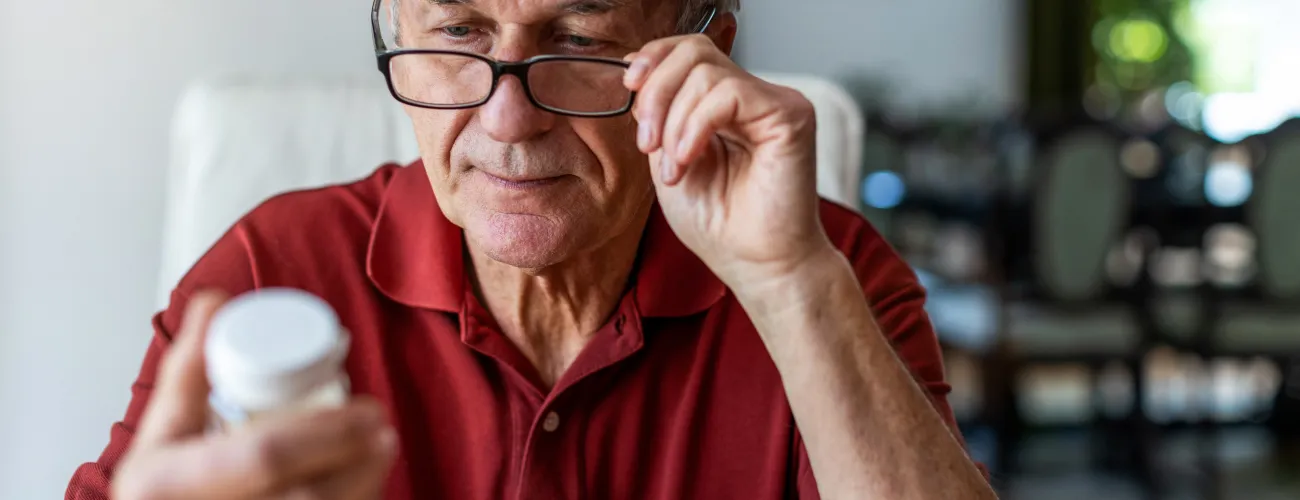 un homme regarde une boite de médicaments