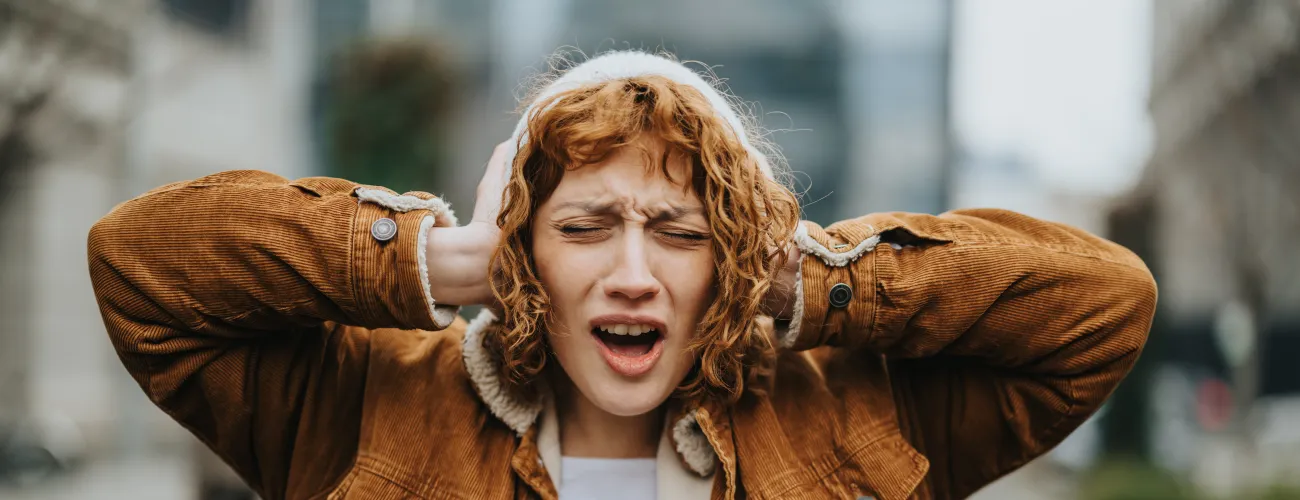 une fille se couvre les oreilles 