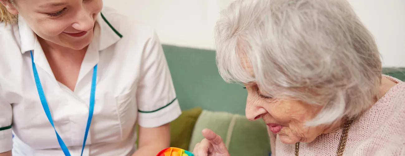 Une infirmière à domicile présente un jeu à une vieille dame