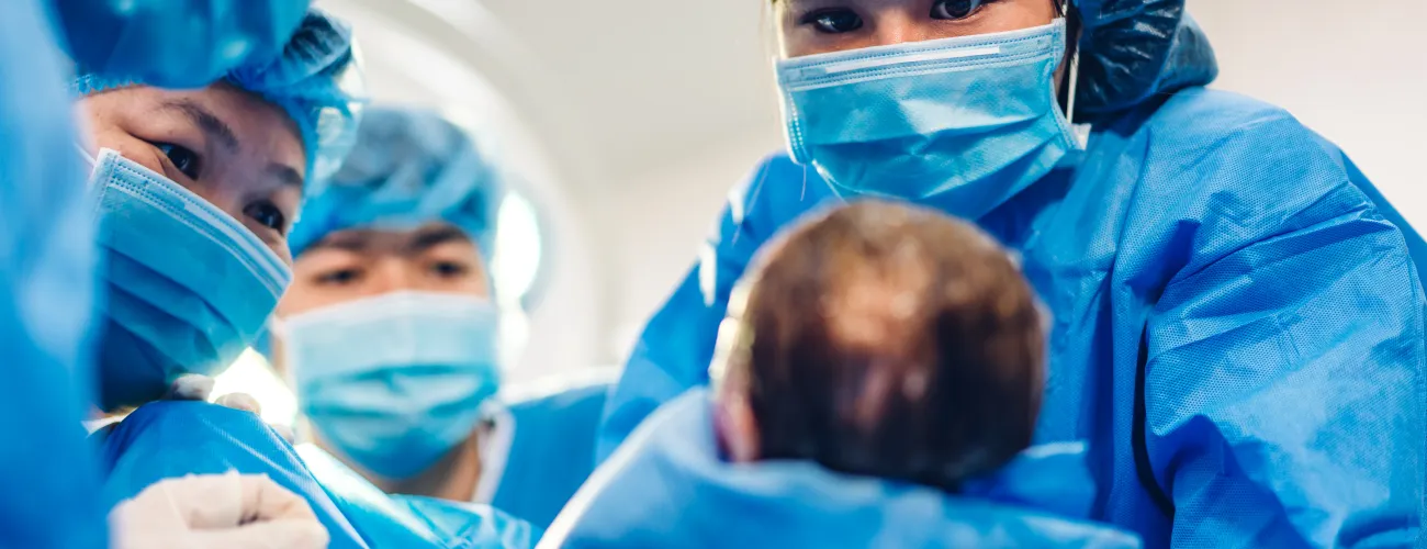 une sage femme tient un enfant dans ses mains lors d'un accouchement très médicalisé