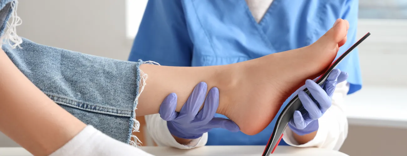 une technologue orthopédique plaque une semelle sur la voûte plantaire d'un patient