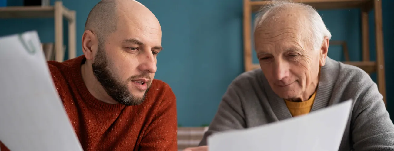 Deux hommes assis à une table comparent des documents