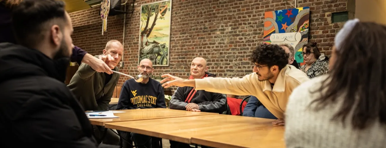 Une animatrice donne une louche à un jeune homme autour d'une table.
