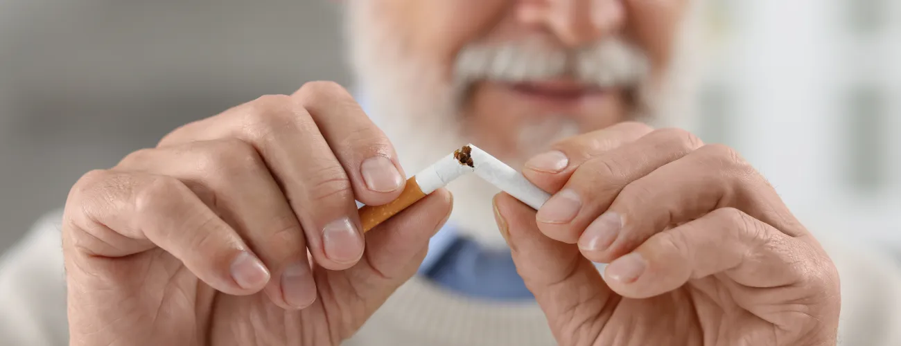 Un homme âgé casse en deux une cigarette
