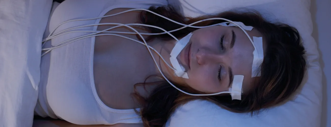 Une jeune femme étendue sur un lit, sous électrodes