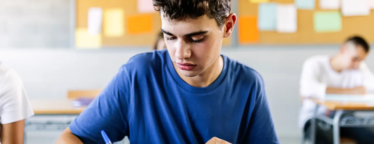 un jeune homme écrit en classe