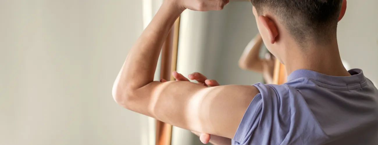 Un ado mesure sa musculature devant le miroir