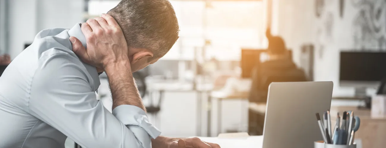Au bureau, un travailleur qui a mal au dos se tient la nuque 