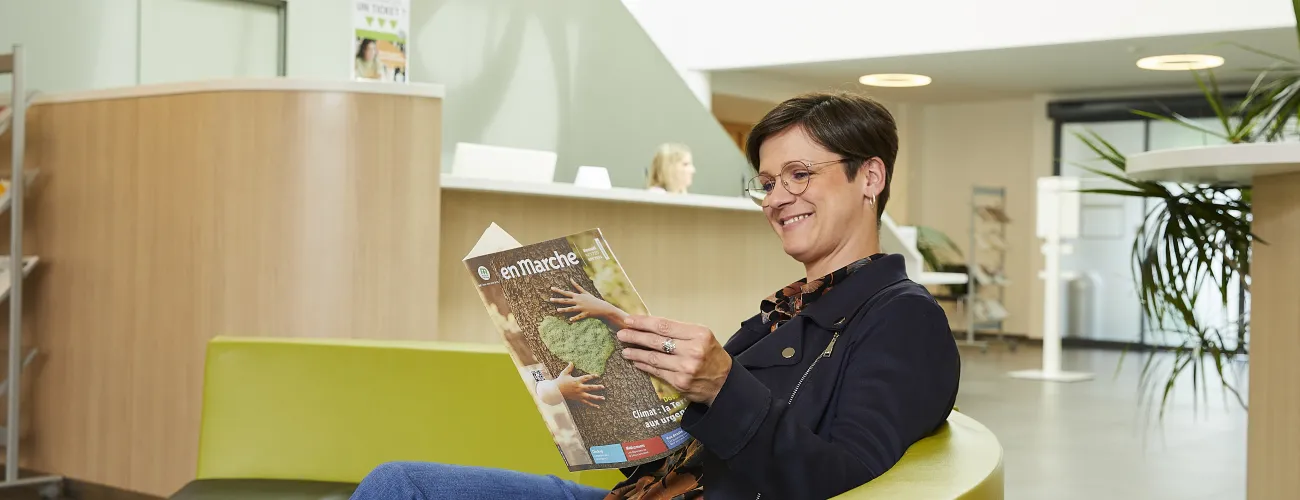 Une femme lit le magazine En Marche dans une agence MC
