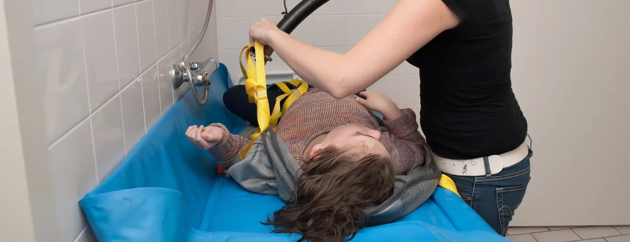 Une maman lave son enfant handicapé couché sur un coussin