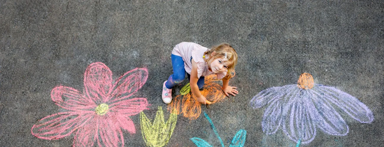 petite fille qui dessine des fleurs sur le béton