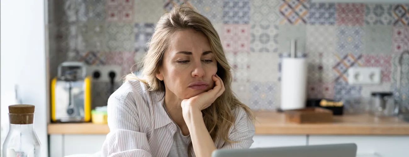 Une femme de la quarantaine regarde son ordinateur l'air dépité