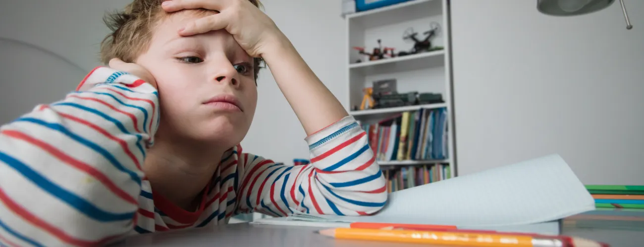 un enfant essaie de se concentrer à sa table de travail