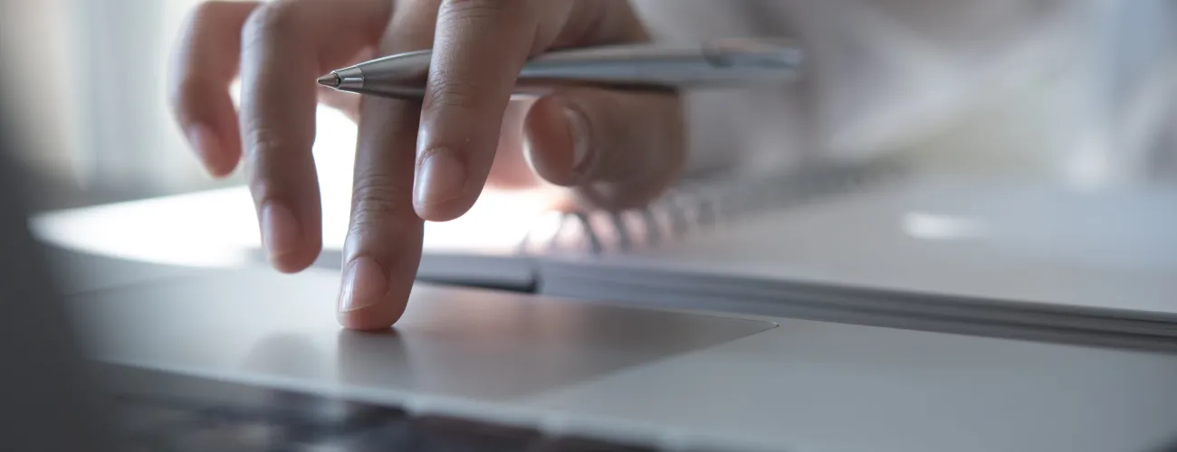 gros plan d'une main sur un clavier avec un stylo en main