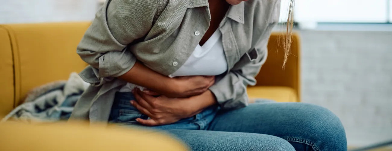 une femme tient le bas de ventre de douleur