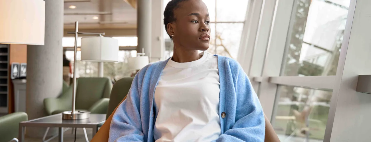 une jeune fille d'origine africaine assise pensive dans un bureau
