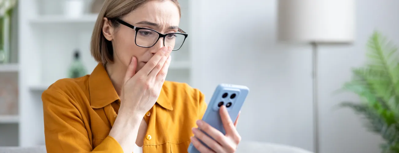 Une jeune femme apeurée devant ce qui s'affiche sur son smartphone.