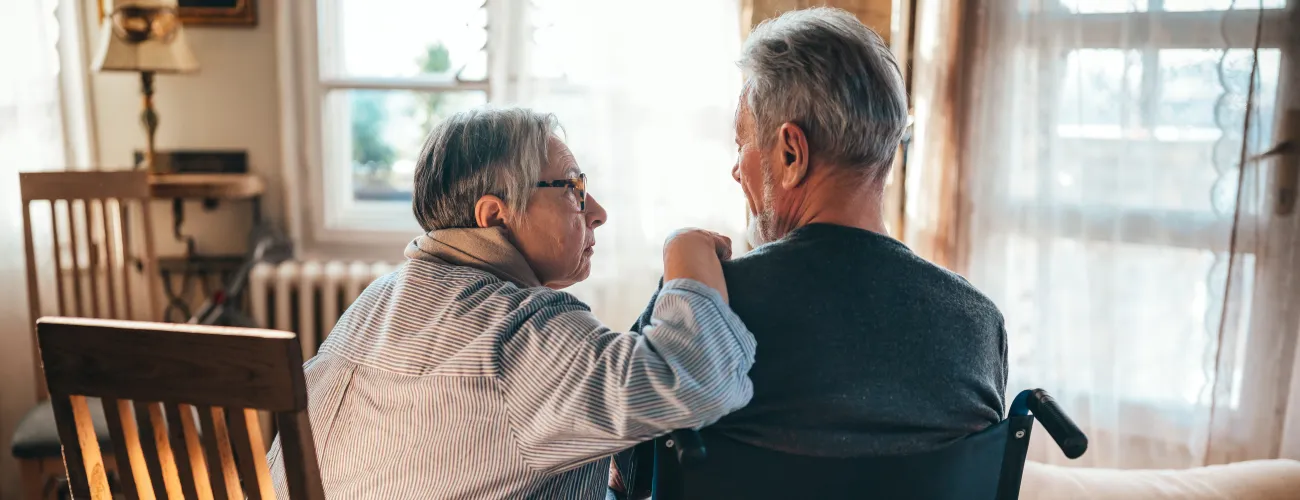 un monsieur en fauteuil roulant converse avec la personne qui l'aide