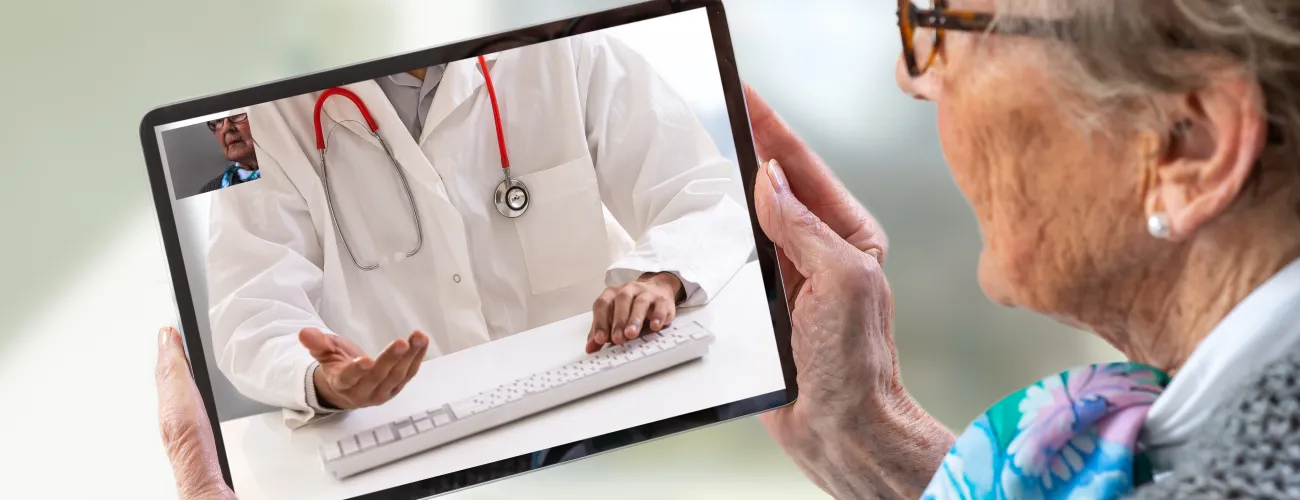 une dame âgée consulte son médecin en ligne sur tablette