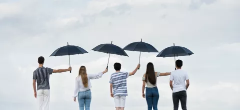 Cinq personnes de dos qui se tiennent un parapluie 