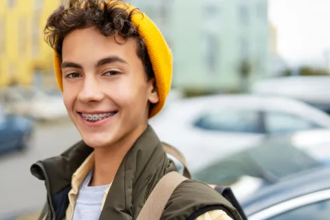 Un adolescent sourit et on voit son appareil dentaire.