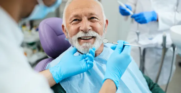 Un homme avec des implants et prothèses dentaires en consultation chez le dentiste